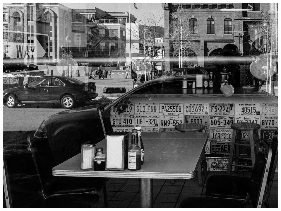 Restauranttisch mit Gewürzen, Flaschen, US-Nummernschildern und Straße im Hintergrund