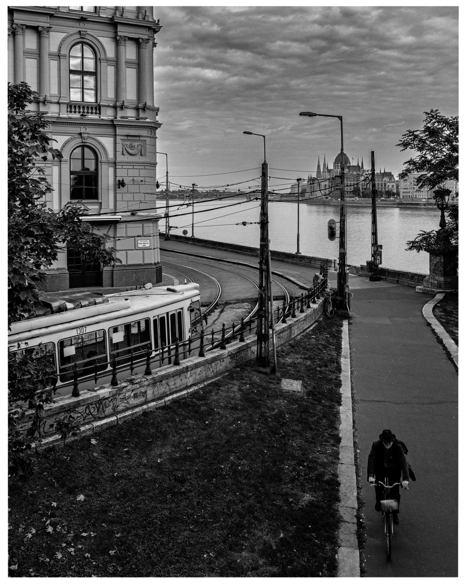 Schwarz-weiße Stadtansicht mit Straßenbahn, historische Gebäude, Fluss und gotische Architektur.