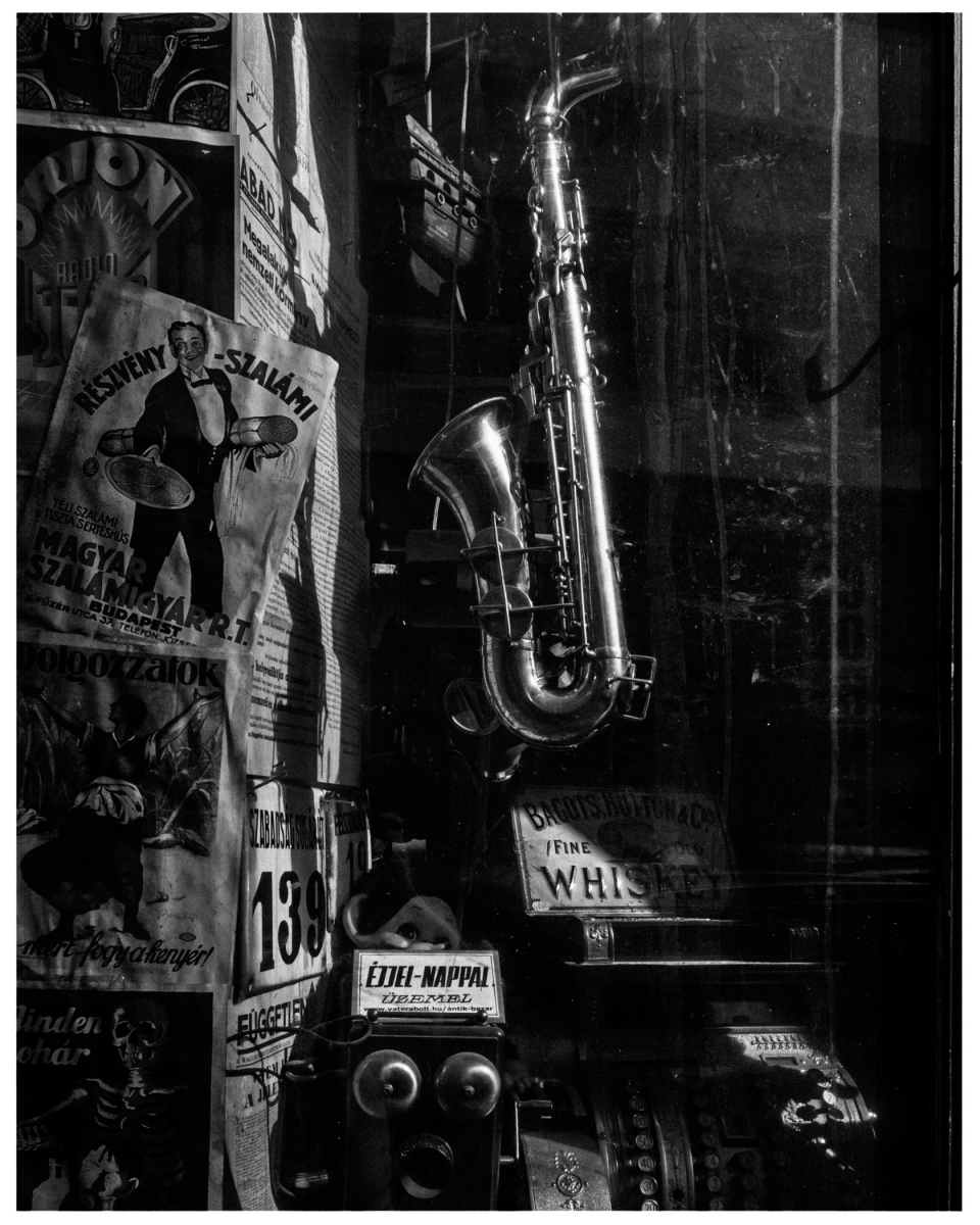 Wand mit alten Werbeplakaten, Saxophon und Registrierkasse, nostalgische Atmosphäre.