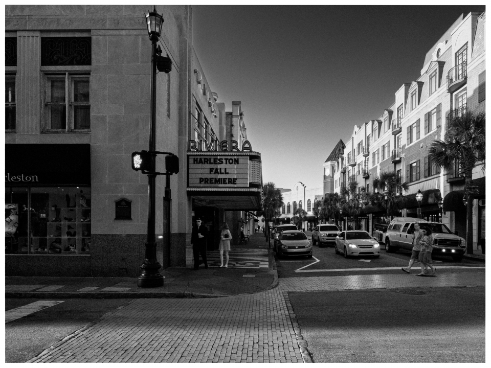 Schwarz-weiße Straßenszene mit Kino "Riviera" und "Harleston Fall Premiere"-Schild.