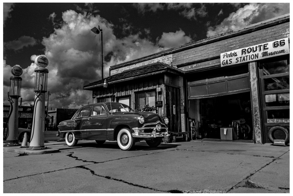 Klassisches Auto vor Pete's Route 66 Gas Station Museum mit nostalgischen Zapfsäulen.