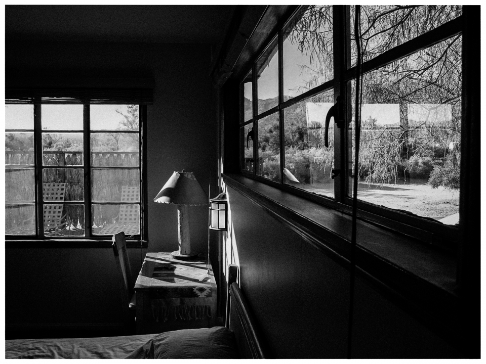 Innenraum mit Holztisch, Tischlampe und Fenster mit Blick auf Bäume und Landschaft.