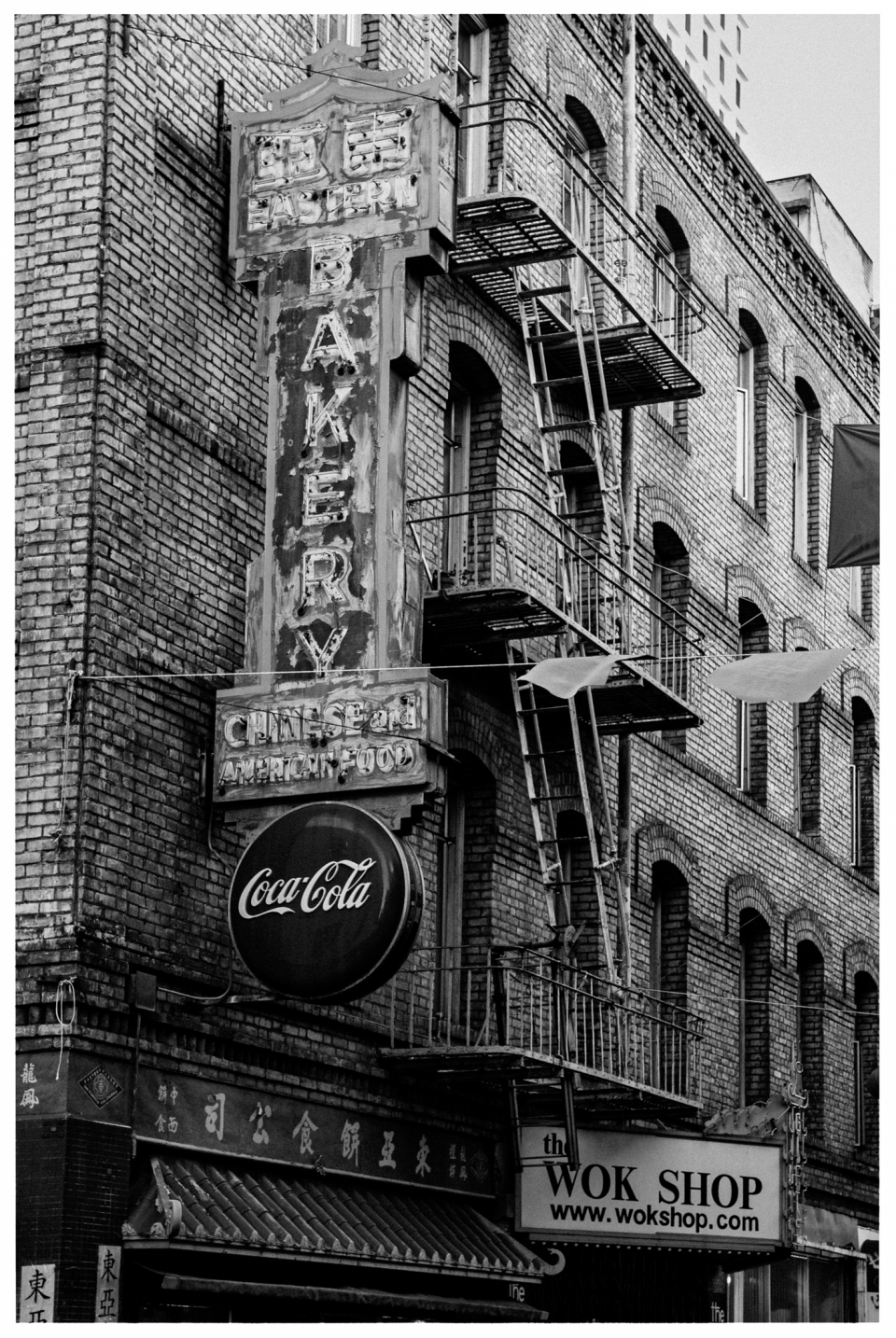 Backsteinfassade mit Bäckerei-Schild für chinesisch-amerikanische Speisen, Coca-Cola-Logo sichtbar.