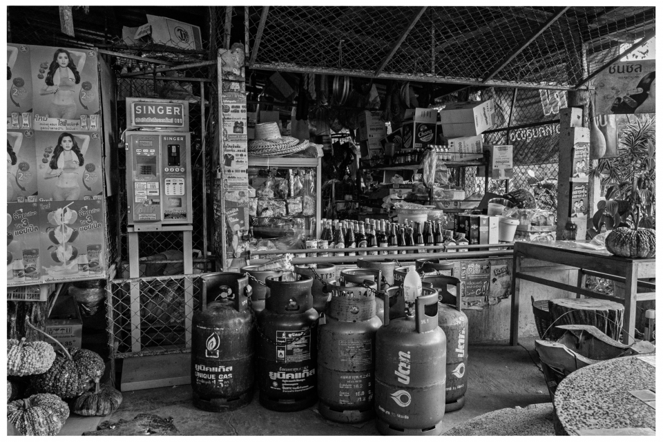 Kleiner Laden mit Gasflaschen, Getränke in Regalen und Plakaten an den Wänden.