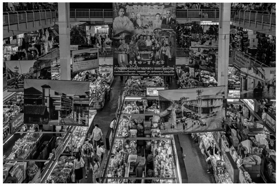 Geschäftiger Innenmarkt mit Ständen, großen Bannern und vielen Menschen in engen Gängen.