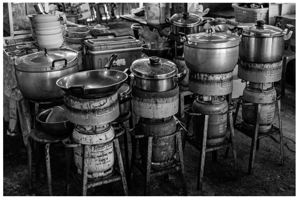 Kochtöpfe und Pfannen auf Gasherden in einer geschäftigen Küche.